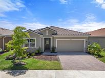 Charming single-story home featuring a well-manicured lawn, brick paved driveway, and a two-car garage at 20450 Revival Ln, Venice, FL 34293