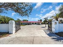 Gated estate entrance featuring a long driveway leading to a single-story home with a red roof at 2211 Englewood Rd, Englewood, FL 34223
