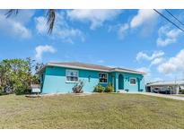 The bright blue single-story house has a well-kept lawn and welcoming entrance on a sunny day at 328 Channel Ln, Nokomis, FL 34275