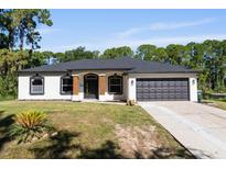 Charming single-story home featuring a well-manicured lawn and a two-car garage at 3470 Elias Cir, North Port, FL 34288