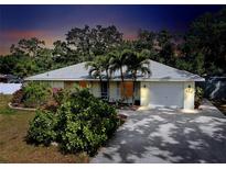 Charming single-story home featuring a well-manicured front yard, attached garage and mature trees at 420 Zephyr Rd, Venice, FL 34293