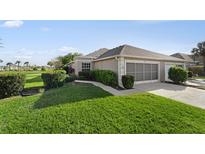 Well-maintained home exterior with a two-car garage, beautiful landscaping, and a lush lawn at 4553 Fairway Dr, North Port, FL 34287