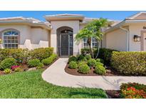 Charming single-story home featuring a stucco facade, manicured landscaping, and a welcoming arched entryway at 867 Macaw Cir, Venice, FL 34285