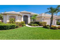 Charming single-story home featuring a well-manicured lawn, lush landscaping, and a welcoming front entrance at 867 Macaw Cir, Venice, FL 34285
