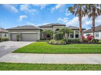 Charming single-story home with well-maintained landscaping, palm trees, and a paver driveway at 988 145Th Street Ne Cir, Bradenton, FL 34212