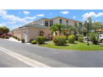 Beautiful peach-colored condo featuring tropical landscaping and elegant architecture, enhancing curb appeal at 1007 Gondola Park Dr # 1007, Venice, FL 34292