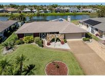 Waterfront home boasts mature landscaping, stone entry arch, and convenient circular driveway at 1229 Waterside Ln, Venice, FL 34285