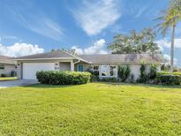 Charming single-story home with a well-manicured front lawn and lush landscaping at 1234 Pinebrook Way, Venice, FL 34285