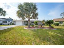 Charming single-story home with a well-manicured lawn, lush landscaping, and a two-car garage at 1311 Pine Needle Rd, Venice, FL 34285