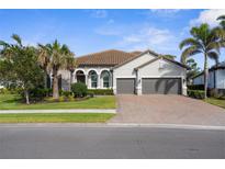 Beautiful exterior of a stucco home with a brick driveway and two-car garage at 19825 Bridgetown Loop, Venice, FL 34293