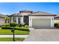 Charming single-story home with a tile roof, well-manicured landscaping, and a brick driveway at 20479 Pezzana Dr, Venice, FL 34292