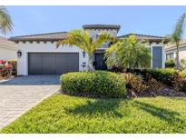 Beautiful single-story home featuring a manicured lawn, paver driveway, and lush landscaping with tropical plants at 208 Corelli Dr, Nokomis, FL 34275