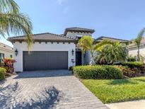 Charming single-story home with a two-car garage, tile roof, paver driveway, and beautifully landscaped front yard at 208 Corelli Dr, Nokomis, FL 34275