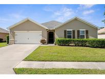 Charming single-story home featuring a well-manicured lawn, two-car garage, and neutral color palette at 25525 Lambert Ln, Punta Gorda, FL 33950