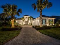 Beautiful home exterior featuring a brick driveway, lush landscaping, and elegant architectural details at twilight at 48 Grande Fairway, Englewood, FL 34223