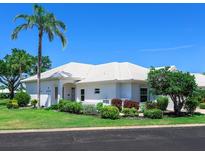 Charming single-story home featuring a white tile roof, lush landscaping, and a vibrant green lawn at 643 Crossfield Cir # 13, Venice, FL 34293