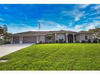 Beautiful single-story home featuring a three-car garage, green lawn, and well-maintained landscaping under a cloudy blue sky at 863 Southland Rd, Venice, FL 34293