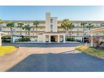 Spacious condo building featuring a grand entrance, covered parking, and tropical landscaping with swaying palm trees at 934 Wexford Blvd # 934, Venice, FL 34293