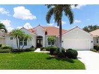 Charming single-story home boasts a red tile roof, lush landscaping, and a well-manicured lawn at 1028 Grouse Way, Venice, FL 34285