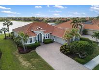Beautiful waterfront home with a tile roof, well-manicured landscaping, and a brick paver driveway at 109 Montelluna Dr, North Venice, FL 34275