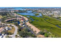 Beautiful aerial view of waterfront condos near lush greenery and a winding coastal inlet at 1130 Bird Bay Way # 184, Venice, FL 34285