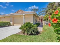 Charming villa featuring lush landscaping, a tile roof, and a welcoming entryway with a covered porch at 121 Auburn Woods Cir, Venice, FL 34292