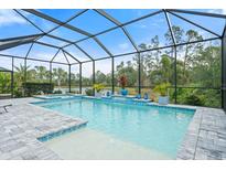 Relaxing screened pool area featuring a jacuzzi and view of mature trees and blue sky at 12456 Destin Loop, Venice, FL 34293
