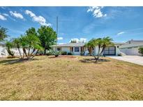Charming single-story home with well-maintained landscaping and mature palm trees under a sunny sky at 1281 Wilson Dr, Englewood, FL 34224