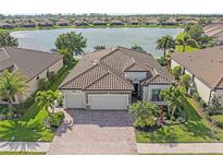 Stunning lakefront home with a tile roof, paver driveway, and lush landscaping at 13215 Amerigo Ln, Venice, FL 34293