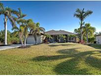 Charming home with a well-manicured lawn, mature palm trees, and an attached garage at 14352 Pocono Ave, Port Charlotte, FL 33981