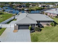 Waterfront home featuring a two-car garage and a well-manicured lawn with direct access to the canal at 1503 Marlin St, Nokomis, FL 34275