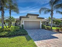 Charming single-story home featuring lush landscaping and a paved driveway leading to an attached garage at 19124 Mangieri St, Venice, FL 34293