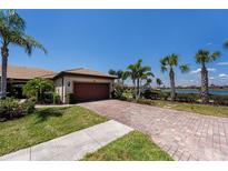 Charming home featuring a tile roof, brick driveway, a two-car garage, and attractive landscaping at 19297 Serafina, Venice, FL 34293