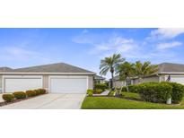 Charming single-story home featuring a two-car garage, well-manicured landscaping, and mature palm trees at 3419 Lakewood Blvd, North Port, FL 34287