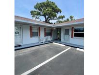 Charming exterior view of cottages with white siding, red shutters, and Adirondack chairs at 510 Airport E Ave # 2C, Venice, FL 34285