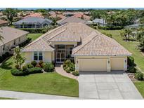 Charming yellow home with a tile roof, well-manicured lawn, and a spacious two-car garage at 615 May Apple Way, Venice, FL 34293