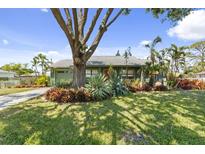 Charming home featuring lush landscaping, a mature shade tree, and a well-manicured lawn at 888 Kimball Rd, Venice, FL 34293