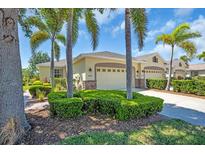Charming home featuring a two-car garage, manicured landscaping, and beautiful palm trees enhancing its curb appeal at 9413 Carnaby Dr, Venice, FL 34293