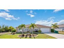 Charming single-story home with well-manicured lawn, complemented by young palm trees, and a two car garage at 10047 Greetings St, Port Charlotte, FL 33981