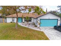 Charming single-story home featuring a bright turquoise garage door and entry in a well-maintained yard at 1008 Euclid Rd, Venice, FL 34293