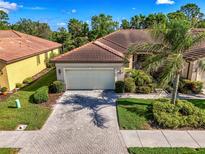 Beautiful villa with a paver driveway, tile roof, well-manicured lawn, and lush landscaping at 11096 Campazzo Dr, Venice, FL 34292