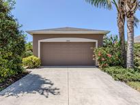 Attached garage with driveway, and landscaping on a sunny day at 11924 Tempest Harbor Loop, Venice, FL 34292