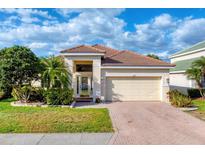 Charming single-story home with a well-manicured lawn, lush landscaping, and a brick-paved driveway at 2094 Mesic Hammock Way, Venice, FL 34292