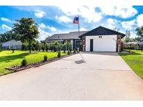 Charming home featuring a manicured lawn, a modern two-car garage, and a welcoming entrance at 23 Tiffany St, Englewood, FL 34223