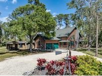 Charming log home with green accents, a gravel driveway, and lush landscaping at 2450 Flagami Ln, North Port, FL 34286
