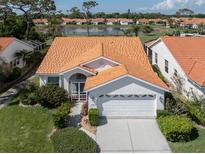Beautiful single-story home with a bright terra cotta roof, manicured lawn, and attached two car garage at 4843 Orange Tree Pl, Venice, FL 34293
