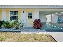 Inviting home entrance with yellow door, window shutters, and tidy landscaping at 595 Circlewood Dr # Y4, Venice, FL 34293