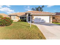 Charming single-story home featuring a beautiful tile roof, a well-manicured lawn and an attached two-car garage at 8300 Parkside Dr, Englewood, FL 34224