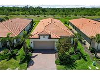 Aerial view of the home with its beautiful terracotta roof, well-manicured landscaping, and a paver driveway at 24153 Spartina Dr, Venice, FL 34293