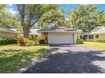 Charming home with a paved driveway leading to an attached garage, surrounded by lush landscaping and mature trees at 269 Southampton Dr # 303, Venice, FL 34293